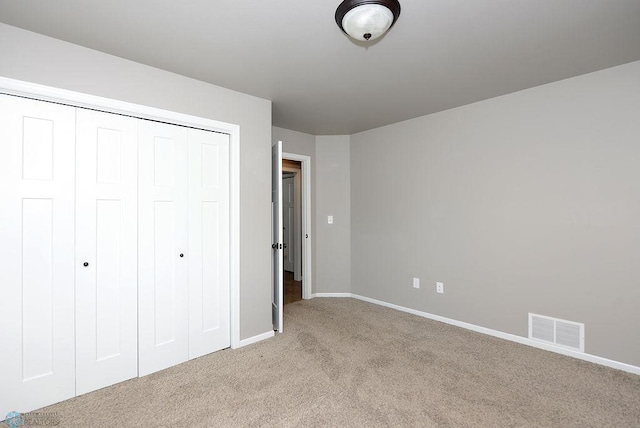 unfurnished bedroom featuring light carpet and a closet