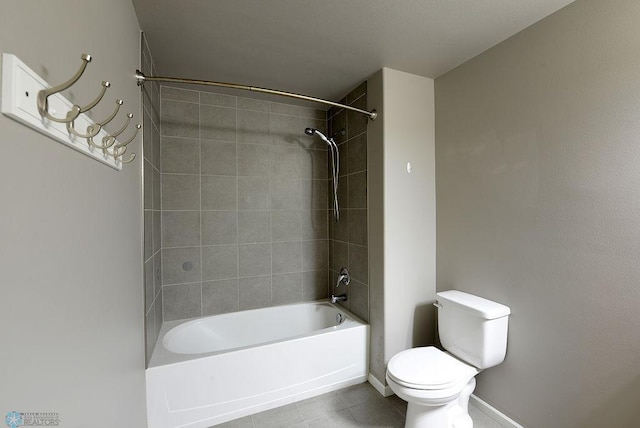 bathroom with tiled shower / bath combo, toilet, and tile patterned floors