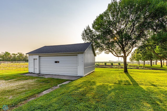 garage at dusk featuring a yard and a rural view