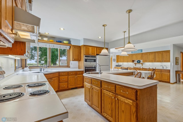 kitchen with an island with sink, hanging light fixtures, white fridge, and sink