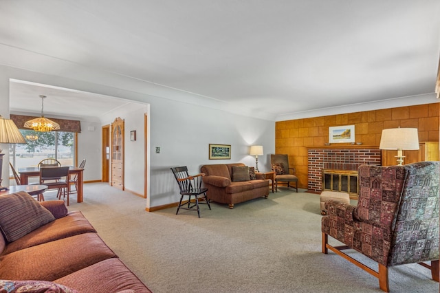 carpeted living room with wood walls, a fireplace, a chandelier, and crown molding