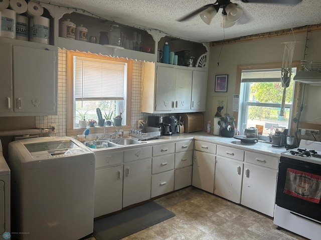 kitchen featuring backsplash, sink, white gas stove, white cabinets, and washer / clothes dryer