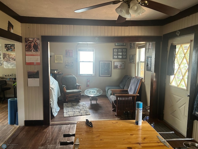 living room featuring hardwood / wood-style floors, ceiling fan, wooden walls, and a textured ceiling