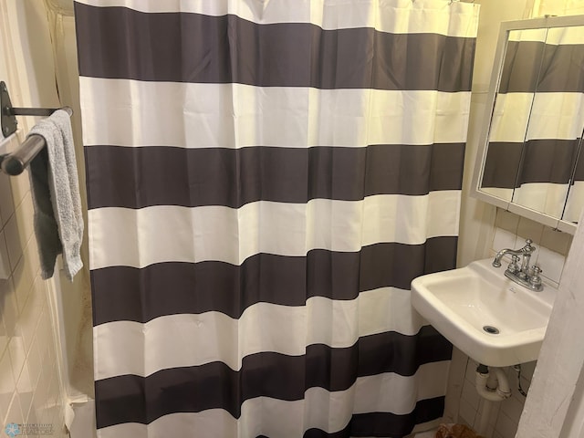 bathroom featuring tile walls, curtained shower, and sink