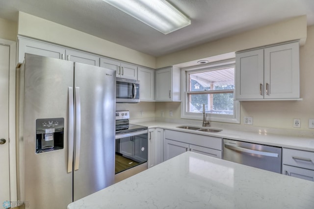 kitchen featuring light stone countertops, appliances with stainless steel finishes, hardwood / wood-style floors, and sink