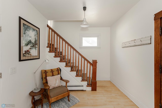 stairs with baseboard heating and hardwood / wood-style flooring