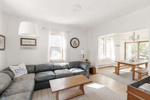 living room with plenty of natural light, light hardwood / wood-style flooring, a baseboard radiator, and a chandelier