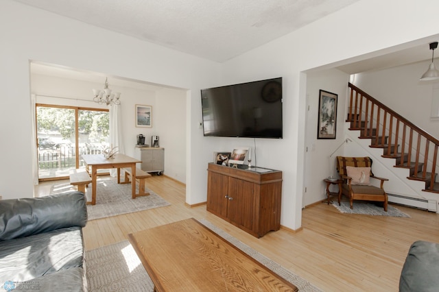 living room with light wood-type flooring, a baseboard heating unit, an inviting chandelier, and a textured ceiling