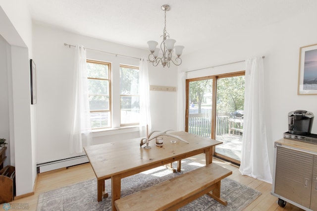 dining room featuring light wood-type flooring, a baseboard heating unit, an inviting chandelier, and a healthy amount of sunlight