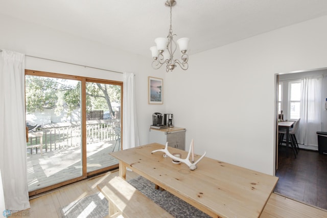 dining space with hardwood / wood-style floors, plenty of natural light, and an inviting chandelier