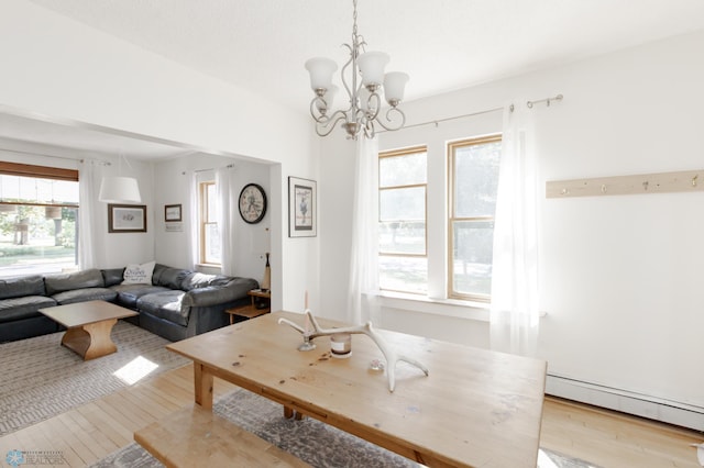 living room with baseboard heating, a chandelier, and light hardwood / wood-style floors