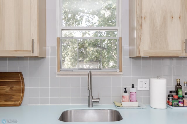 kitchen featuring light brown cabinetry, sink, and decorative backsplash