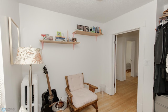 sitting room with a textured ceiling and light hardwood / wood-style flooring