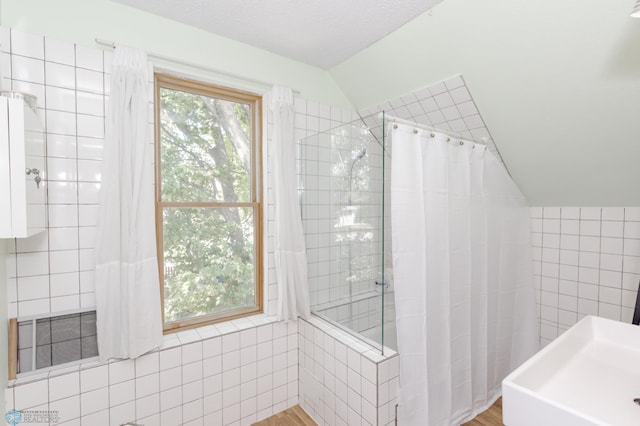 bathroom featuring lofted ceiling, tile walls, wood-type flooring, and curtained shower