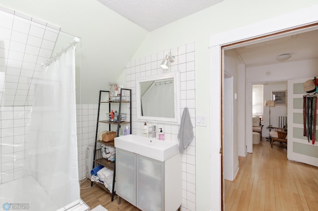 bathroom featuring hardwood / wood-style floors, vanity, a textured ceiling, tile walls, and a shower with shower curtain