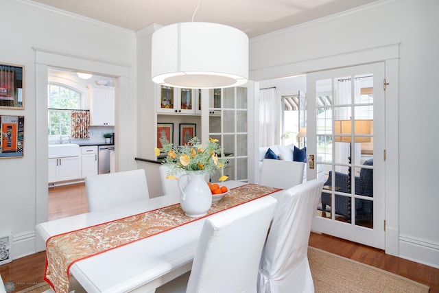 dining room with crown molding, sink, and wood-type flooring