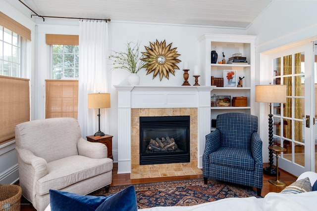 living room featuring dark wood-type flooring, a tiled fireplace, and crown molding