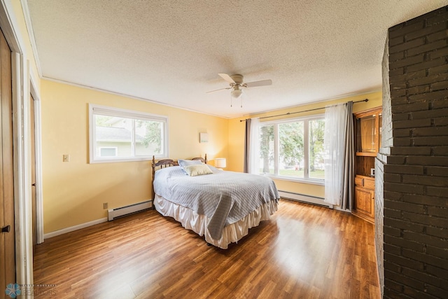 bedroom featuring baseboard heating, hardwood / wood-style floors, multiple windows, and ceiling fan