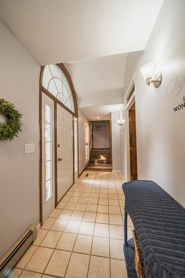 tiled foyer featuring a textured ceiling, lofted ceiling, and a baseboard radiator