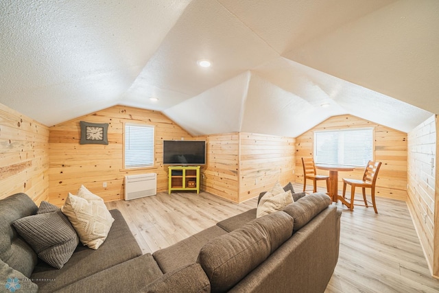 living room with light hardwood / wood-style floors, lofted ceiling, and wooden walls