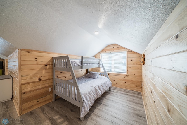 bedroom with wood walls, hardwood / wood-style floors, and a textured ceiling