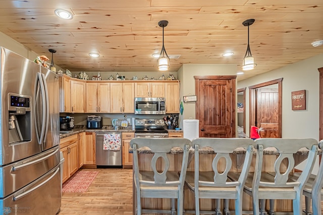 kitchen with a kitchen bar, appliances with stainless steel finishes, hanging light fixtures, and light hardwood / wood-style floors