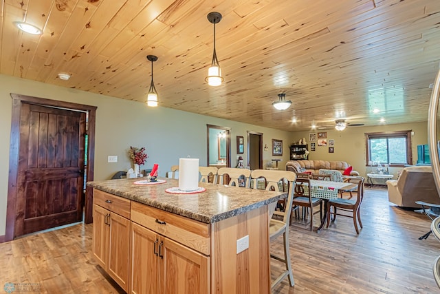 kitchen featuring ceiling fan, wood ceiling, light hardwood / wood-style flooring, a center island, and a breakfast bar