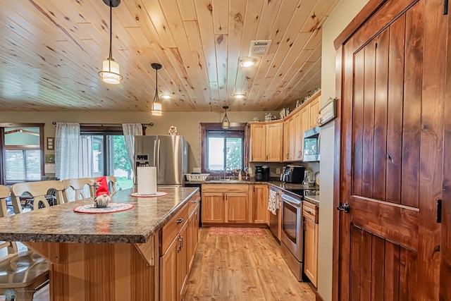 kitchen with hanging light fixtures, light hardwood / wood-style flooring, stainless steel appliances, a center island, and a kitchen bar