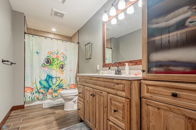 bathroom with a shower with shower curtain, hardwood / wood-style floors, vanity, and toilet