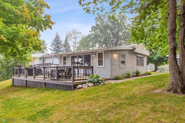 rear view of property featuring a wooden deck and a lawn