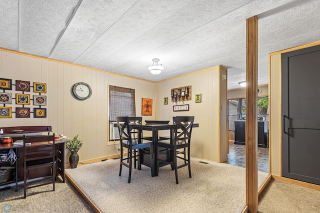 dining space with wooden walls and carpet floors