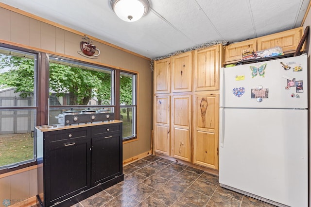 kitchen featuring wood walls, white refrigerator, and light brown cabinets