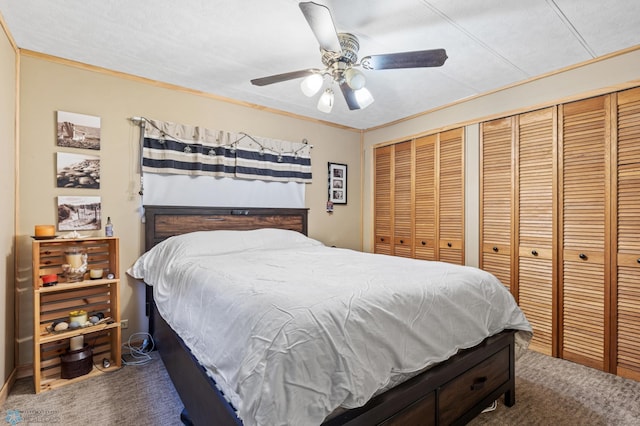 carpeted bedroom with a textured ceiling, two closets, ceiling fan, and crown molding