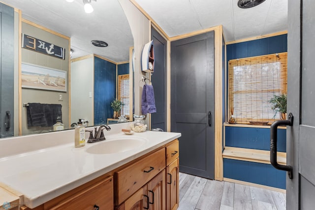 bathroom with crown molding, wood-type flooring, and vanity