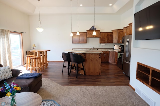 kitchen with a center island, stainless steel appliances, dark hardwood / wood-style floors, pendant lighting, and a breakfast bar