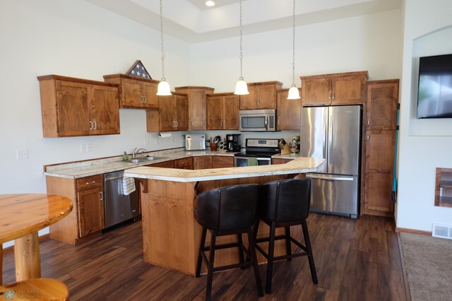 kitchen featuring a kitchen island, dark hardwood / wood-style floors, decorative light fixtures, appliances with stainless steel finishes, and a high ceiling