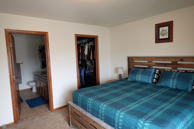 bedroom featuring a walk in closet, a closet, ensuite bathroom, and light carpet