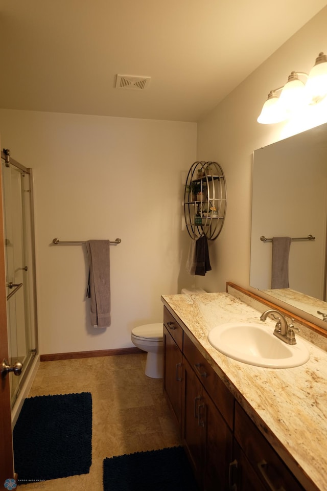 bathroom with vanity, toilet, and a shower with shower door