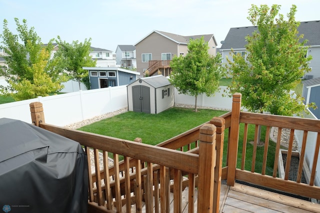 wooden terrace featuring area for grilling, a lawn, and a shed