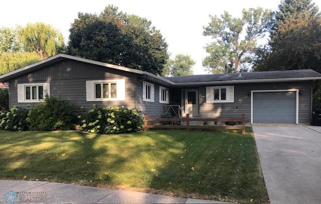 ranch-style home with a garage and a front lawn