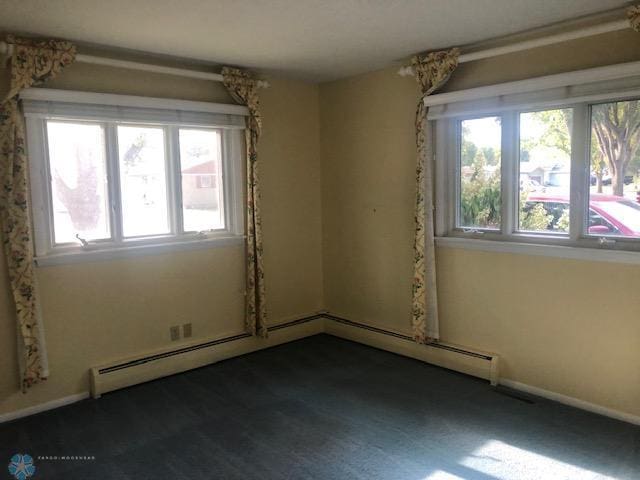 carpeted spare room featuring a baseboard radiator and plenty of natural light