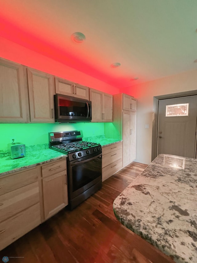 kitchen with light brown cabinets, range with gas stovetop, dark hardwood / wood-style floors, and light stone countertops