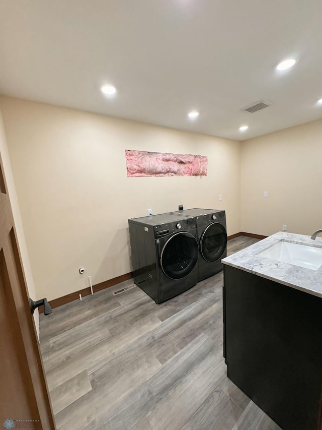 laundry room with sink, light hardwood / wood-style floors, and washer and dryer