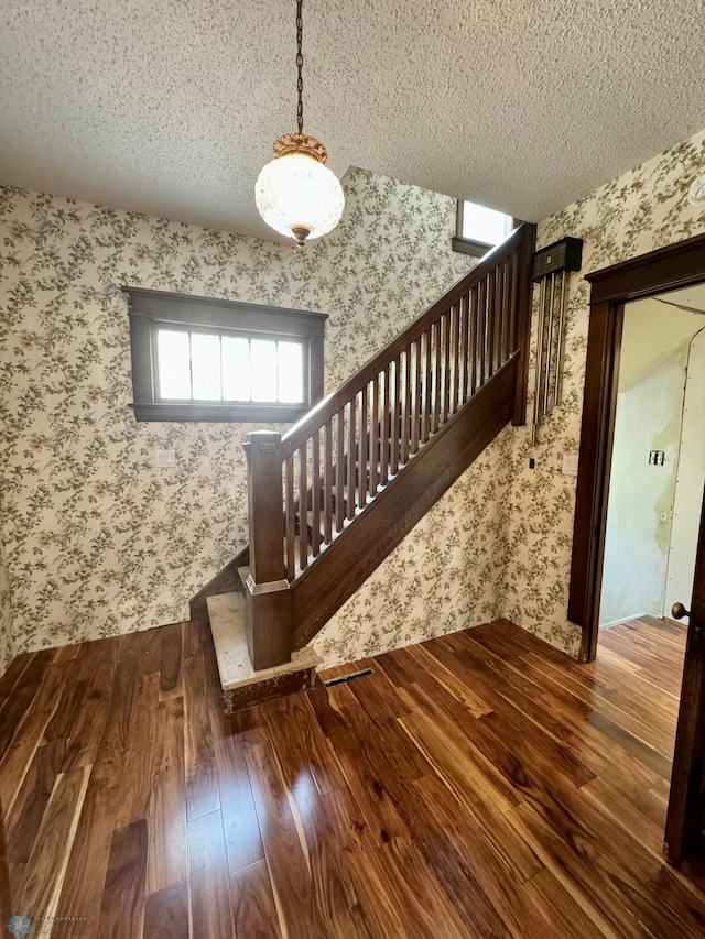 stairs featuring a textured ceiling and wood-type flooring