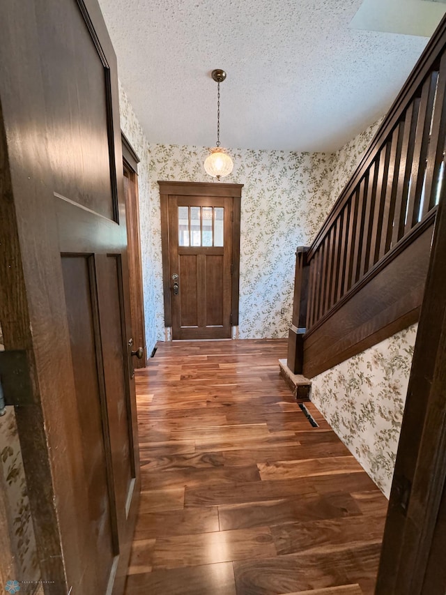 entryway with dark wood-type flooring and a textured ceiling