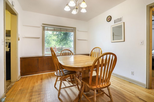 dining space featuring light wood-type flooring and a notable chandelier