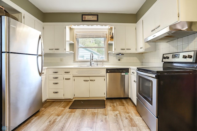 kitchen featuring tasteful backsplash, sink, appliances with stainless steel finishes, white cabinets, and light hardwood / wood-style floors