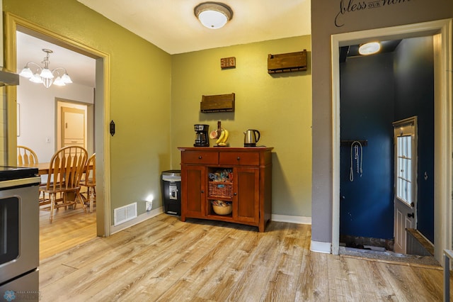 foyer entrance with light wood-type flooring and an inviting chandelier