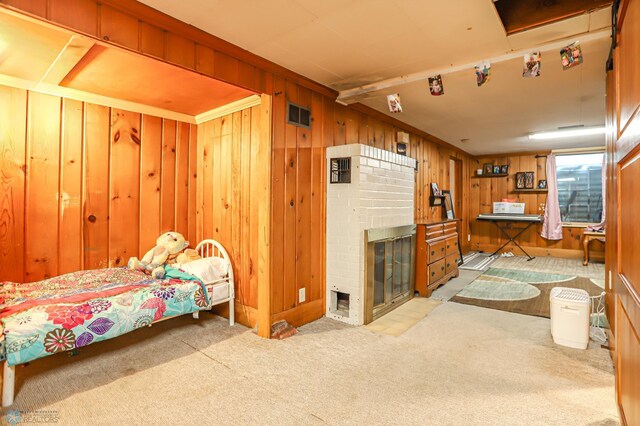 bedroom featuring wood walls, light colored carpet, a fireplace, and beam ceiling