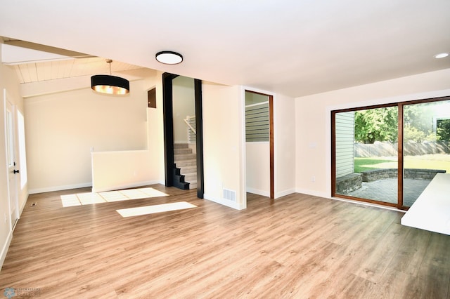 empty room featuring vaulted ceiling with beams and light hardwood / wood-style floors